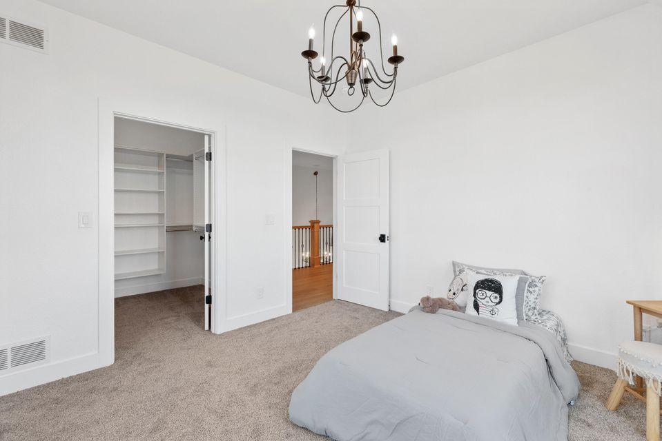 Interior view of bedroom painted white with white trim, with carpeted floor and bed.